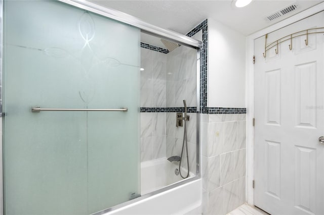 bathroom featuring combined bath / shower with glass door and tile walls