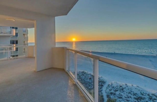 balcony at dusk featuring a water view