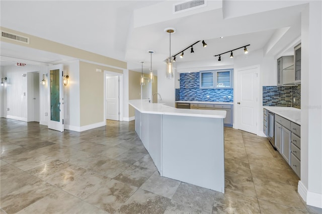 kitchen featuring gray cabinetry, sink, hanging light fixtures, backsplash, and a kitchen island with sink