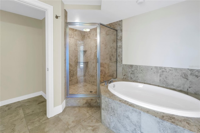 bathroom featuring tile patterned floors, a stall shower, baseboards, and a garden tub