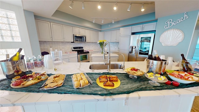 kitchen with tasteful backsplash, a peninsula, stainless steel appliances, and a sink