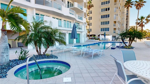 pool with a patio area and a community hot tub