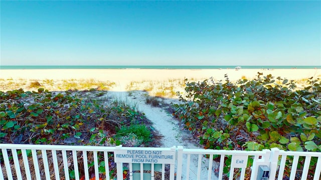 view of water feature featuring fence and a beach view