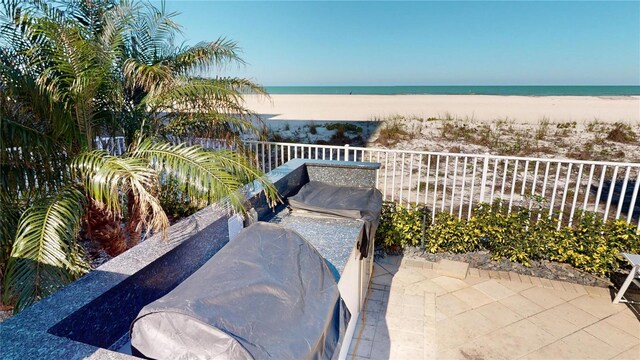 view of patio featuring fence, a beach view, and a water view