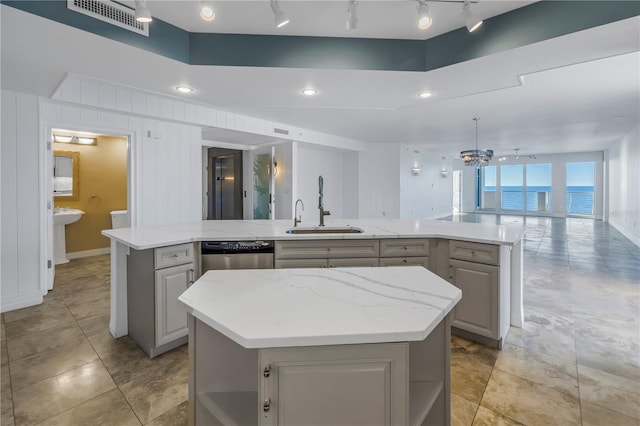 kitchen featuring a sink, visible vents, gray cabinetry, open floor plan, and an island with sink