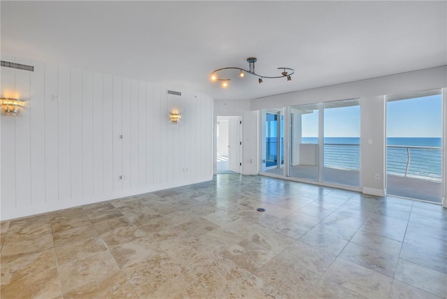 spare room featuring a chandelier, visible vents, a water view, and baseboards