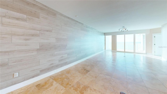 empty room featuring an inviting chandelier and an accent wall