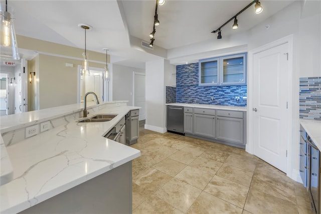 kitchen with stainless steel dishwasher, decorative backsplash, a sink, light stone countertops, and gray cabinets