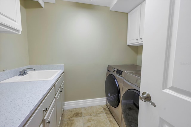 laundry area with baseboards, cabinet space, washing machine and clothes dryer, and a sink