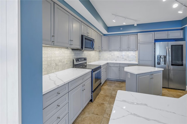 kitchen with gray cabinetry, tasteful backsplash, appliances with stainless steel finishes, and light stone counters