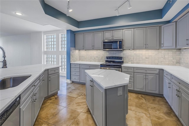 kitchen featuring a sink, tasteful backsplash, track lighting, gray cabinetry, and appliances with stainless steel finishes