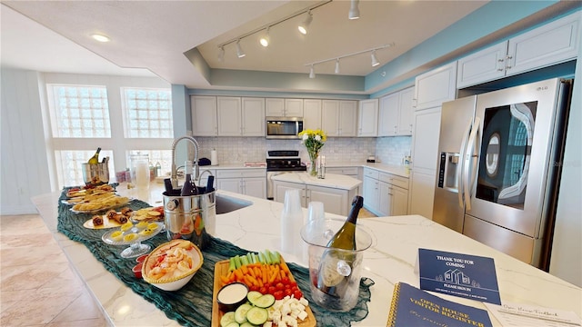 kitchen featuring light stone counters, stainless steel appliances, a center island, light tile patterned flooring, and backsplash