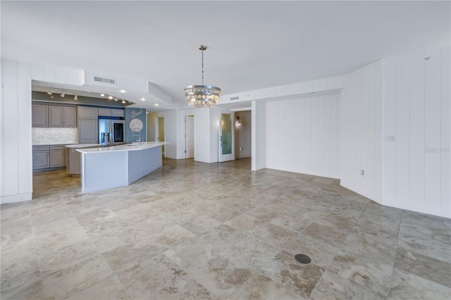 unfurnished living room featuring a sink, visible vents, and a chandelier