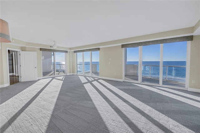 empty room featuring baseboards, ceiling fan, a water view, and carpet flooring