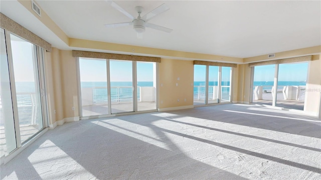 empty room with a ceiling fan, carpet floors, and a water view