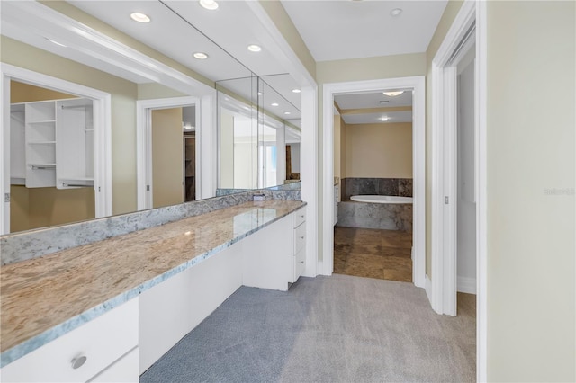full bathroom featuring recessed lighting, a bath, and vanity