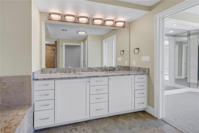 bathroom with baseboards, tile patterned flooring, double vanity, and a sink