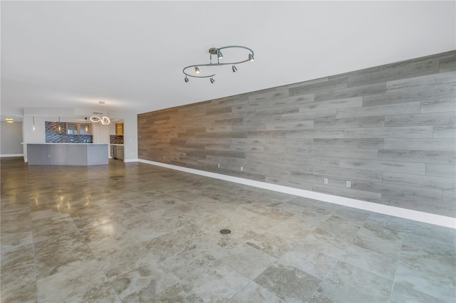unfurnished living room featuring baseboards and an accent wall