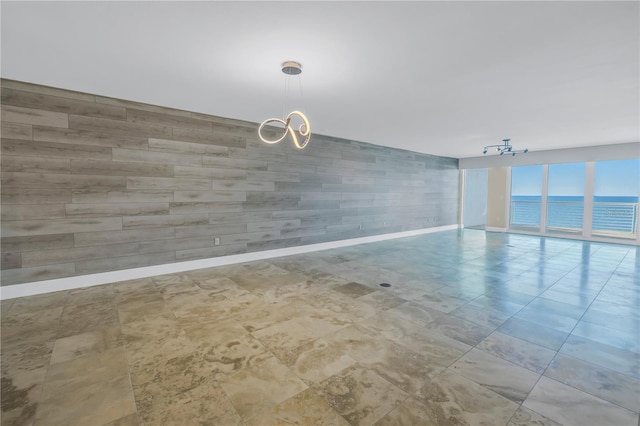 spare room featuring a chandelier, baseboards, and a water view