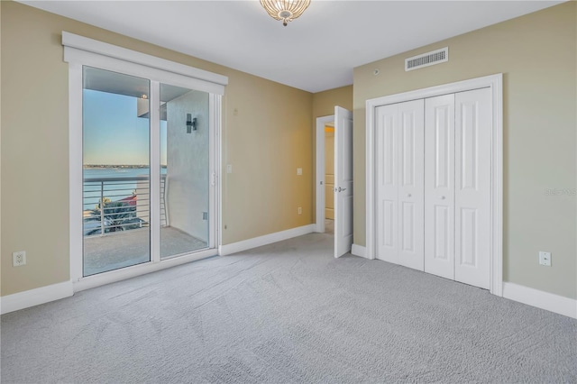 unfurnished bedroom with baseboards, visible vents, carpet floors, and a closet