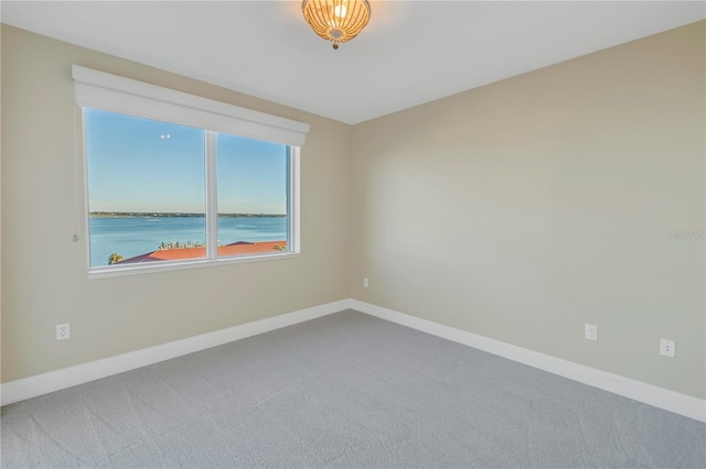 carpeted empty room featuring baseboards and a water view