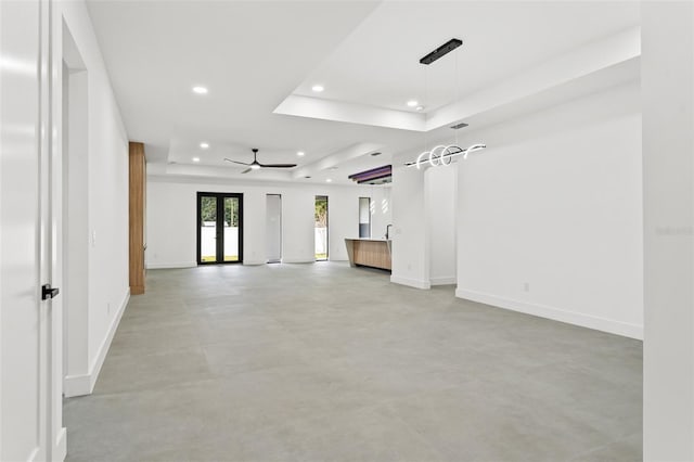 unfurnished room with a raised ceiling, ceiling fan, and french doors