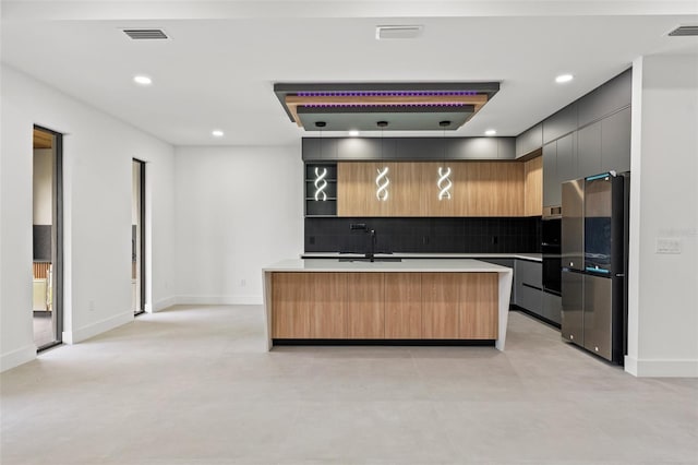 kitchen with stainless steel fridge, a center island, sink, and tasteful backsplash