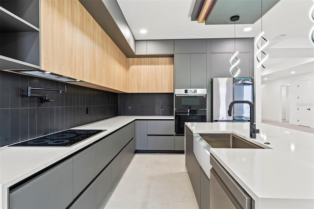 kitchen featuring gray cabinetry, backsplash, decorative light fixtures, light brown cabinetry, and black appliances