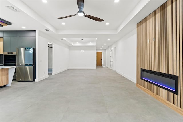 unfurnished living room with a fireplace, a raised ceiling, and ceiling fan