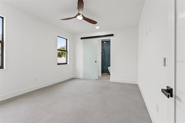 empty room featuring ceiling fan and a barn door