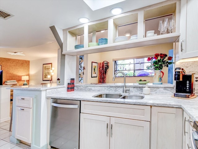 kitchen with light stone counters, light tile patterned flooring, dishwasher, and sink