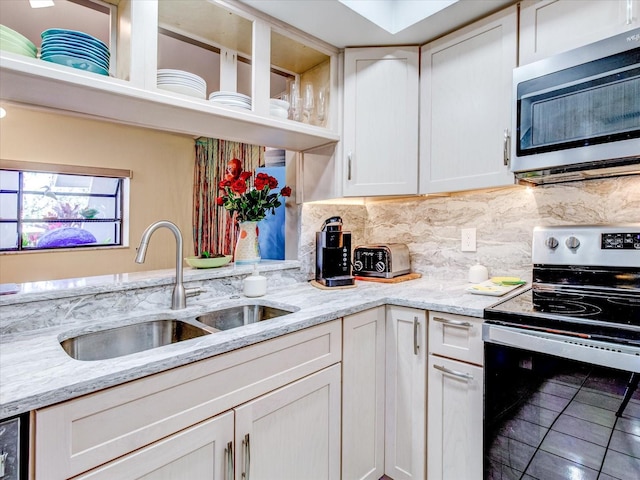 kitchen with sink, white cabinets, light stone counters, and appliances with stainless steel finishes