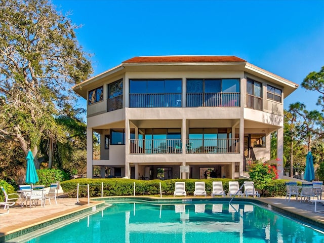 rear view of house with a community pool and a patio