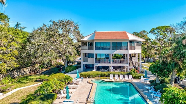 back of property with a balcony, a community pool, and a patio area