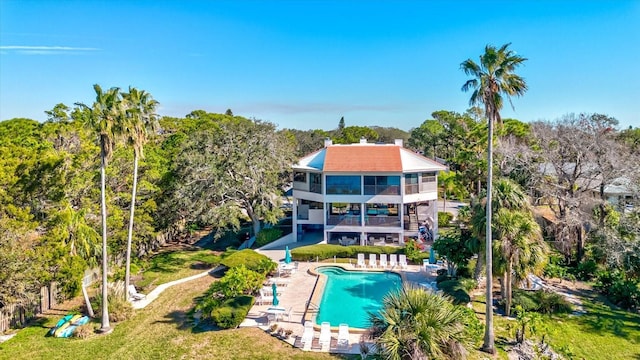 back of house with a balcony, a lawn, and a community pool