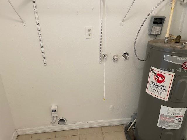 washroom featuring water heater, tile patterned flooring, and hookup for an electric dryer