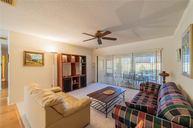 living room with ceiling fan and a textured ceiling