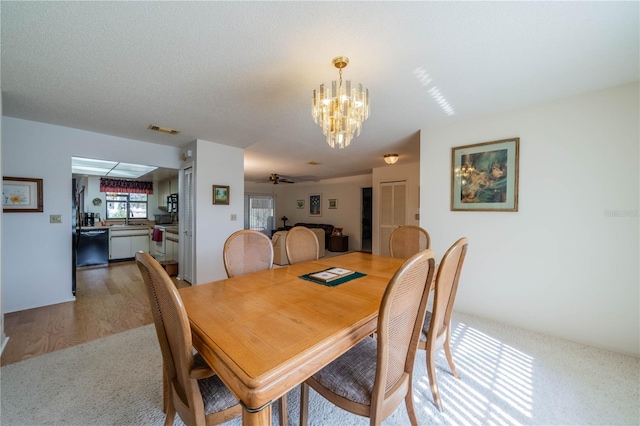 dining area featuring wood-type flooring, sink, ceiling fan with notable chandelier, and a textured ceiling