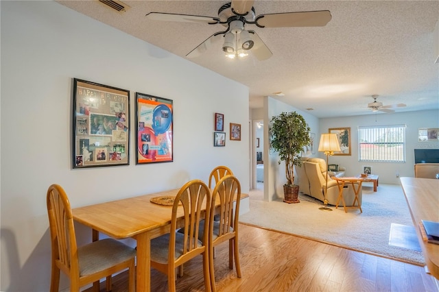 dining area with ceiling fan, a textured ceiling, and light wood-type flooring