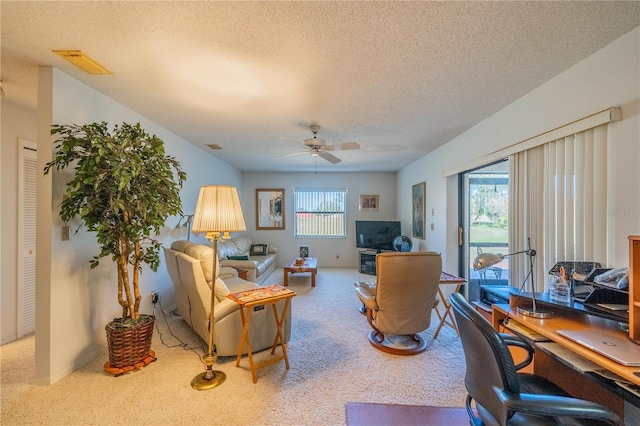 living room featuring ceiling fan, a wealth of natural light, carpet floors, and a textured ceiling