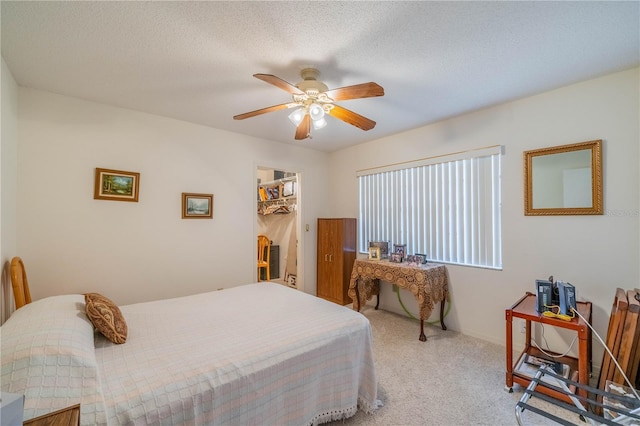 carpeted bedroom featuring a walk in closet, a textured ceiling, ceiling fan, and a closet