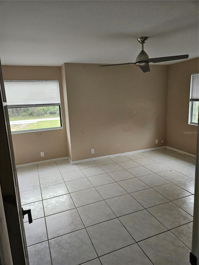 spare room with ceiling fan and light tile patterned floors