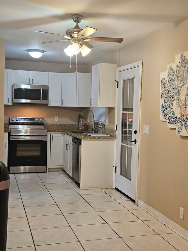 kitchen with ceiling fan, white cabinets, appliances with stainless steel finishes, light tile patterned flooring, and sink