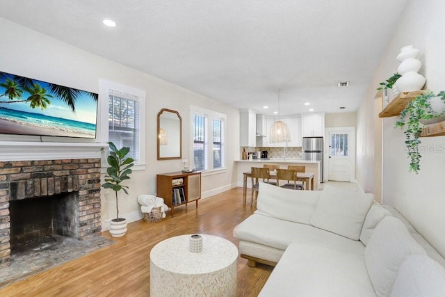 living room featuring a brick fireplace and light hardwood / wood-style floors