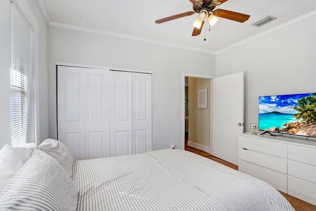 bedroom with crown molding, light hardwood / wood-style flooring, a closet, and ceiling fan