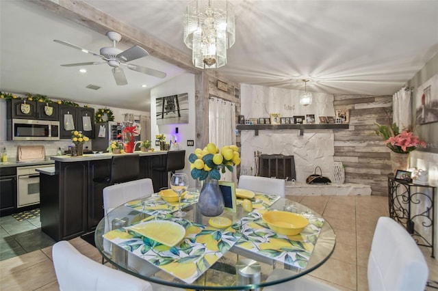 tiled dining room featuring beamed ceiling, a fireplace, and ceiling fan