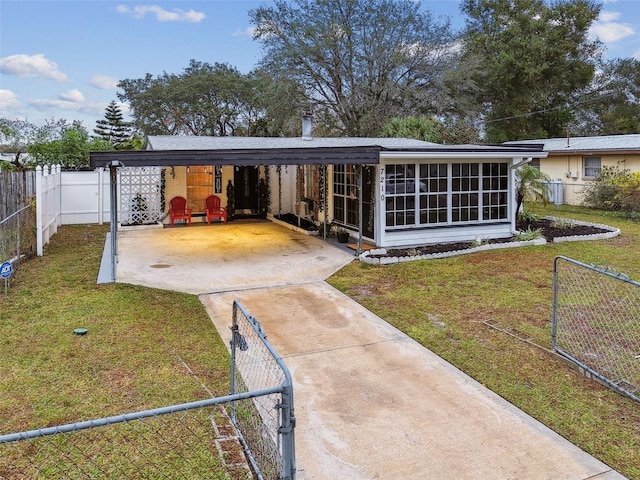 rear view of house featuring a yard, a carport, and a sunroom