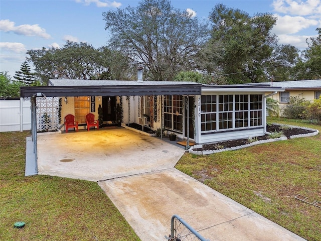 rear view of house featuring a carport, a sunroom, and a yard