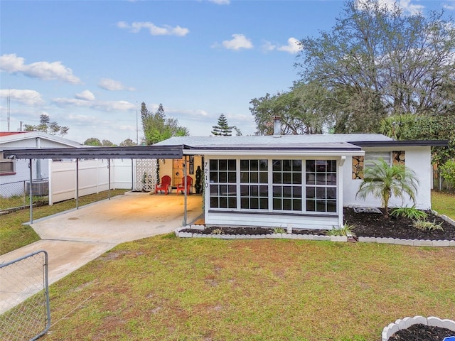 back of property with a lawn and a carport