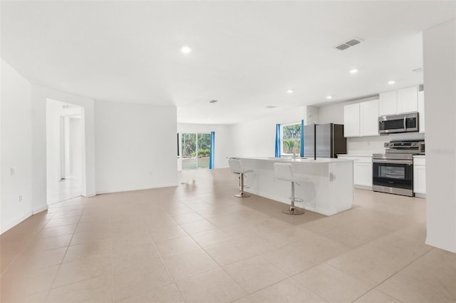 kitchen featuring a center island, a breakfast bar area, light tile patterned floors, white cabinetry, and stainless steel appliances